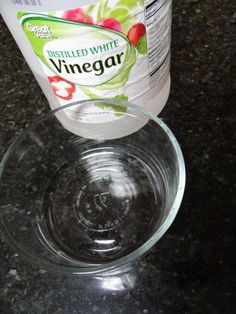 a bottle of vinegar sitting on top of a glass bowl