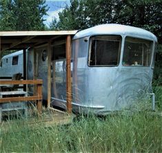 an old trailer sits in the middle of some tall grass