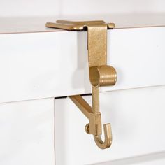 a close up of a metal hook on a white cabinet