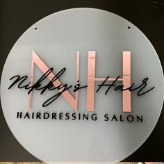 a hair salon sign with pink and black lettering on the front of it, hanging from a wall