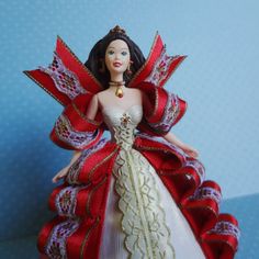 a doll dressed in a red and white dress with gold trimmings on it