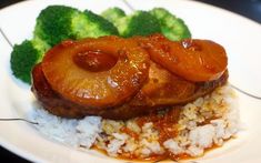 a white plate topped with meat and rice covered in sauce next to broccoli