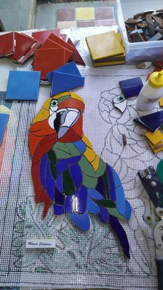 a colorful parrot sitting on top of a table next to scissors and other crafting supplies