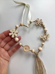 a woman's hand holding a bracelet made out of wood beads and tassels