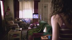 a woman standing in a living room next to a couch and television set on top of a table