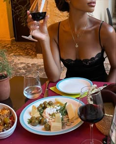 a woman sitting at a table holding a glass of wine