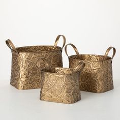 three metal containers with handles and handles on each side, one has a flower design