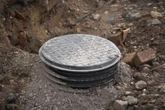 a manhole cover sitting on top of a pile of rocks