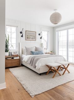 a bed room with a neatly made bed and a chandelier hanging from the ceiling