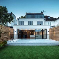 a modern house with grass and trees in the front yard