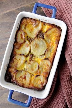 a casserole dish with potatoes in it on a blue and white plate next to a pink towel