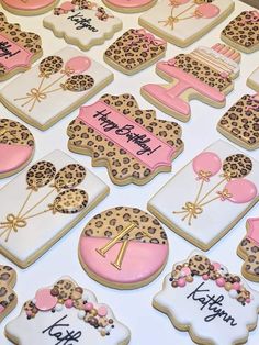 decorated cookies are displayed on a table with pink and white decorations, including leopard print