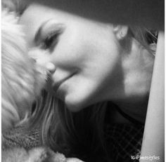 black and white photograph of a woman kissing a dog's face with her eyes closed