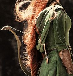 a woman with long red hair wearing a green dress and holding a snake in her hand