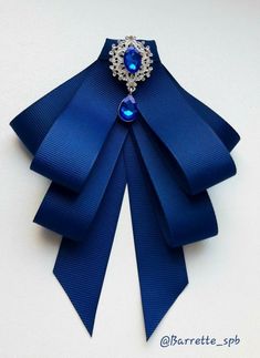 a blue ribbon with a brooch on it's side and a diamond in the center