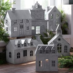 several models of houses are shown in front of a window and potted plant on the floor