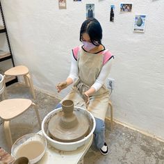 a woman is making a vase out of clay on a potter's wheel in a studio