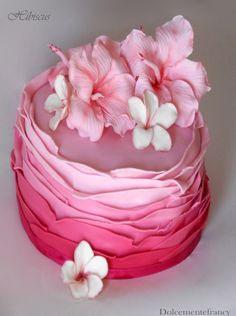 a cake with pink and white frosting has flowers on it's top layer