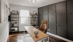 an office with a desk, chair and shelves on the wall in front of it