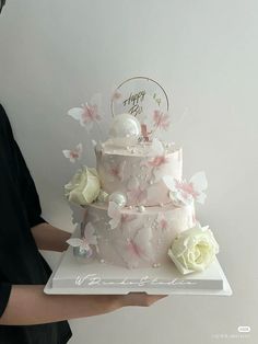 a person holding a cake with flowers on it