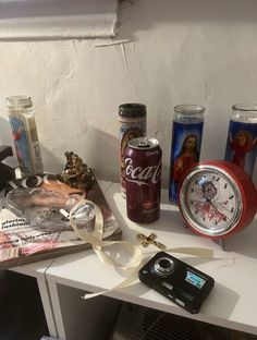 various items are sitting on top of a white table next to an alarm clock and camera