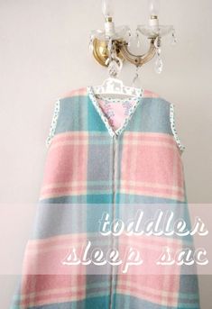 a blue and pink plaid blanket hanging from a hook with the words toddler sleep sack on it