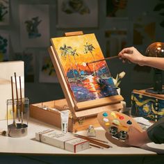 a person is painting on an easel with paintbrushes and other art supplies