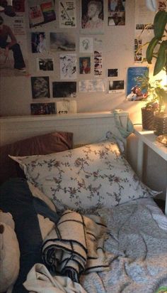 an unmade bed with many pictures on the wall above it and a lamp next to it