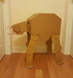 an elephant made out of cardboard sitting on top of a hard wood floor next to a door