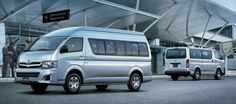 two silver vans parked in front of an airport