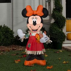 a large inflatable mickey mouse standing on top of a lush green field next to a house