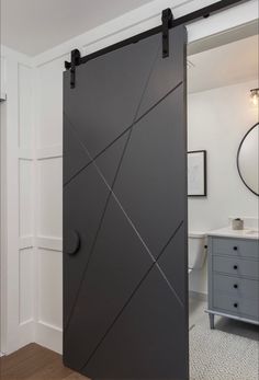 an open sliding door in a bathroom with wood flooring and white walls, next to a gray dresser