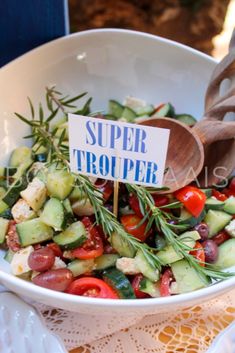 a white bowl filled with cucumber, tomatoes, and other veggies