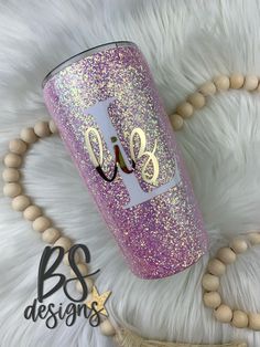 a purple glitter tumbler with the initials blg on it and a beaded necklace