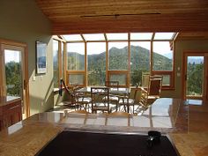 an open kitchen and dining room area with large windows overlooking the mountain range in the distance