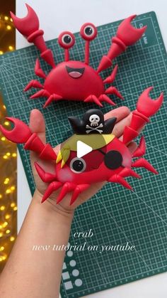 a hand holding a red crab with googly eyes and a pirate eye patch on it