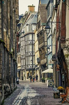 an old street with people walking down it