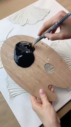 someone using a brush to paint a piece of wood with black paint on top of it