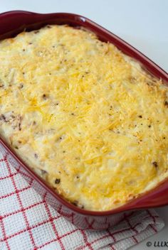 a casserole dish with cheese and meat in it sitting on a red checkered cloth