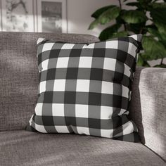 a black and white checkered pillow sitting on top of a couch next to a potted plant