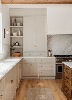 a kitchen with white cabinets and marble counter tops