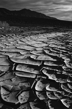 a black and white photo of an empty road in the middle of nowhere with mountains in the background