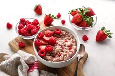 two bowls filled with oatmeal, berries and strawberries on top of a white table