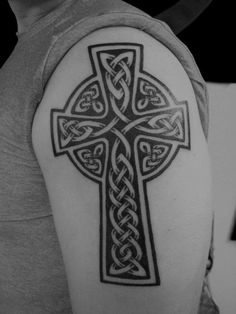 a person with a cross tattoo on their arm and shoulder, in black and white