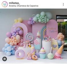 a table topped with lots of balloons and cake next to a wall covered in letters