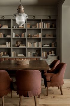 a dining room table and chairs with bookshelves in the background