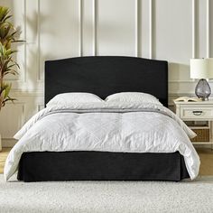 a bed with white sheets and black headboard in a room next to a lamp