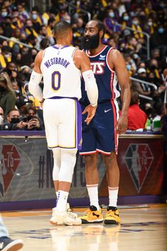 two basketball players standing next to each other in front of an arena full of people