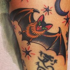 a bat tattoo on the leg of a person with stars and moon in the background