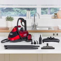 a red and black steam cleaner sitting on top of a kitchen counter next to tools